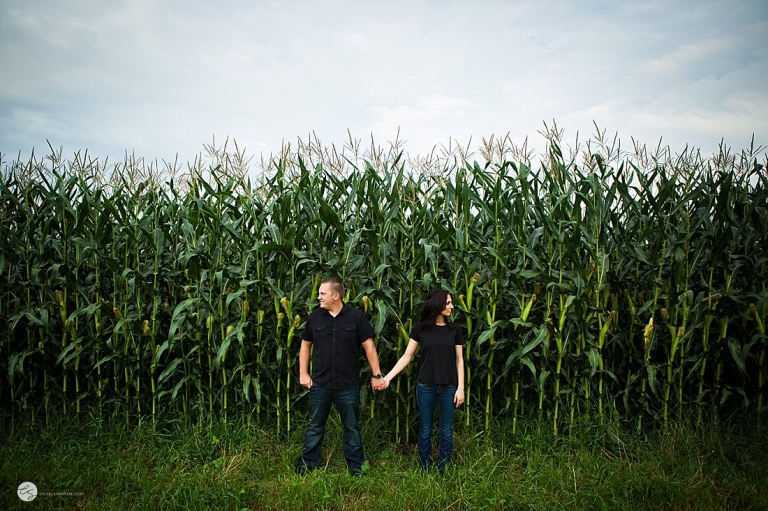 guy and girl holding hands in front of corn field