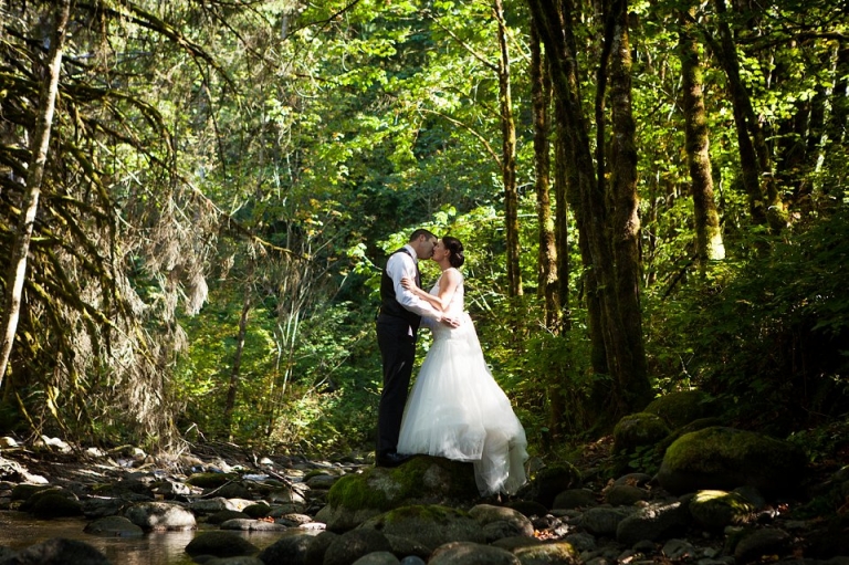 bride and groom standing on river bed 