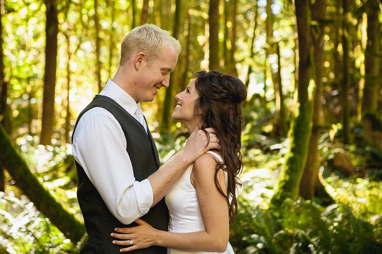 bride and groom smiling at each other in forest
