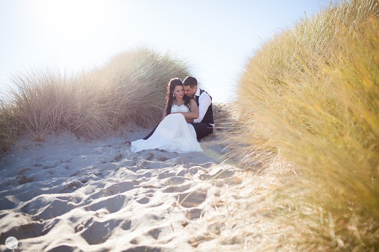 bride and groom cuddling in sand dunes