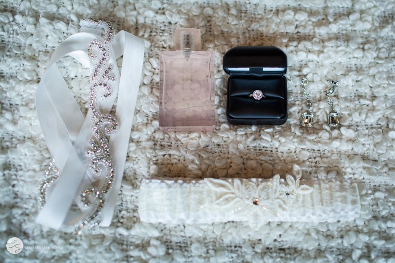 garter, perfume, engagement ring and wedding dress sash on white blanket 