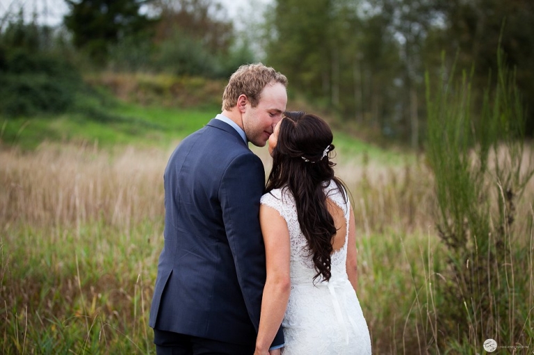bride and groom kissing in field