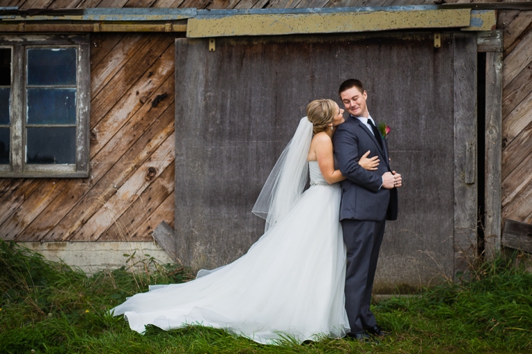 bride and groom hugging in front of barn