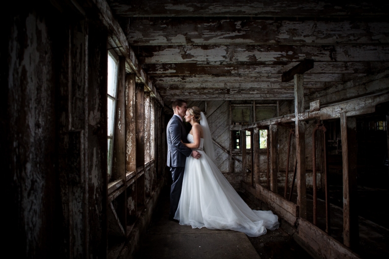 bride and groom hugging in side of a rustic barn