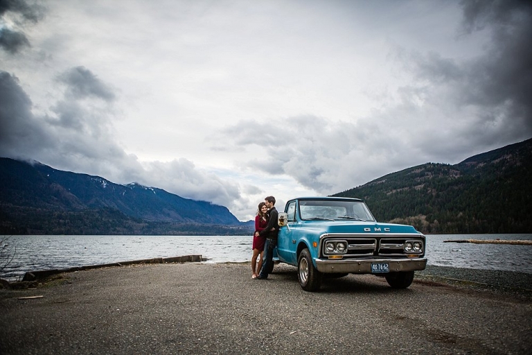 boy and girl snuggling by old blue chevy at cultus lake boat launch