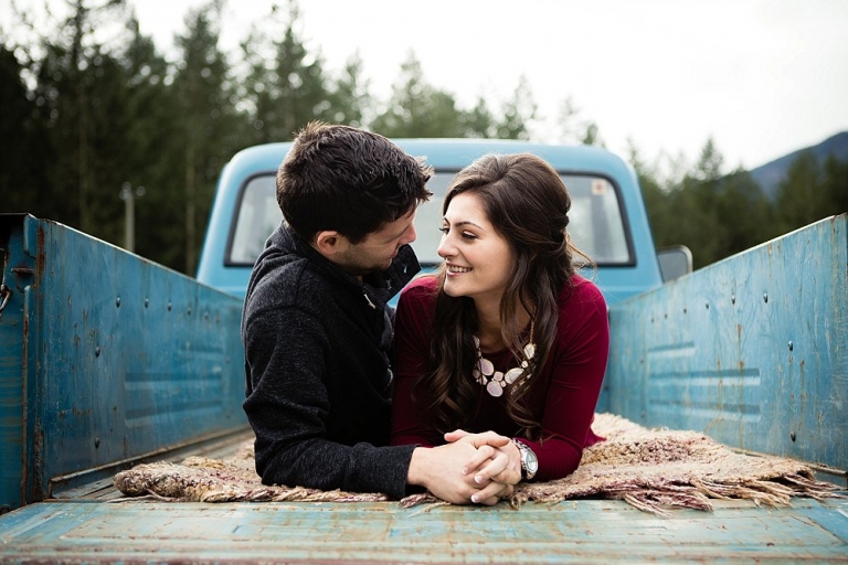 engaged couple laying in the box of an old truck