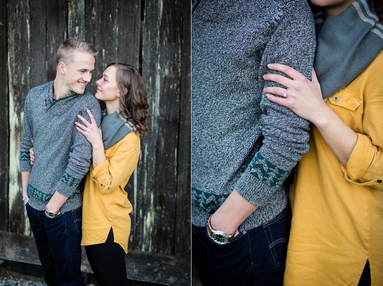 Engaged couple snuggling in front of barn