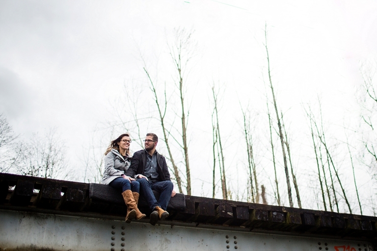 engaged couple sitting on a bridge