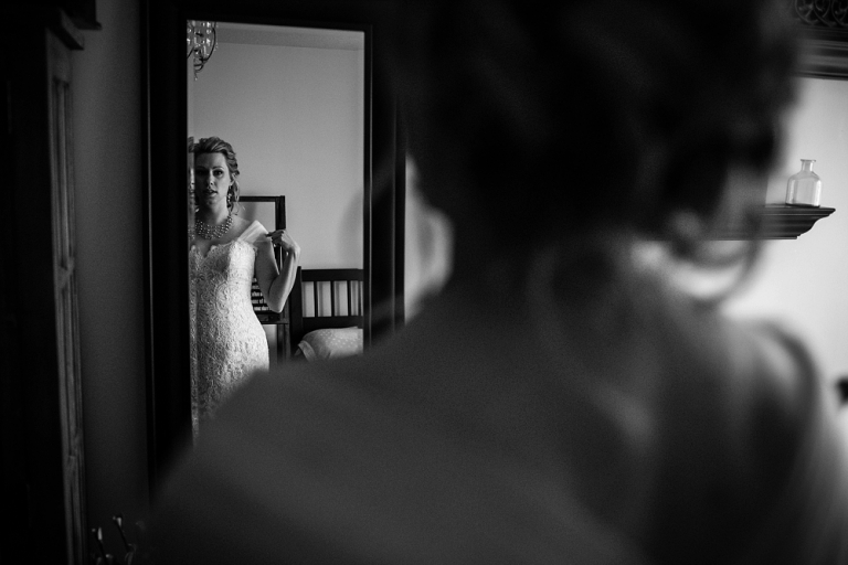 black and white photo of bride looking at herself in the mirror on her wedding day