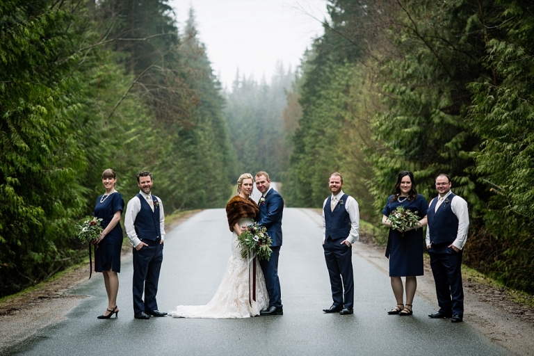 bridal party standing in the middle of a tree lined road