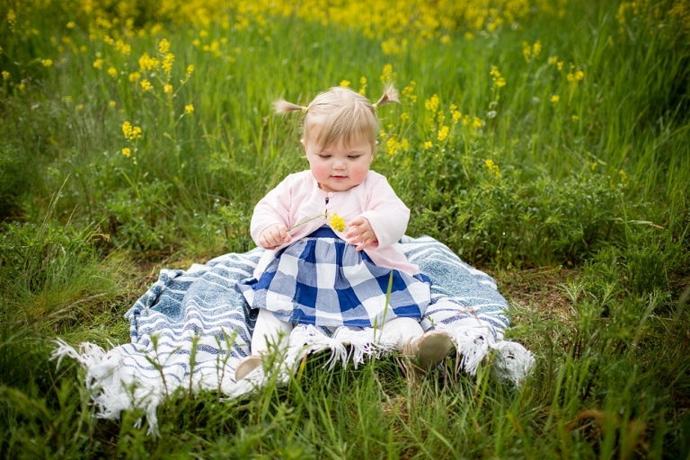 baby girl sitting on blanket in long grasses