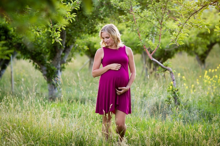 pregnant woman standing in orchard